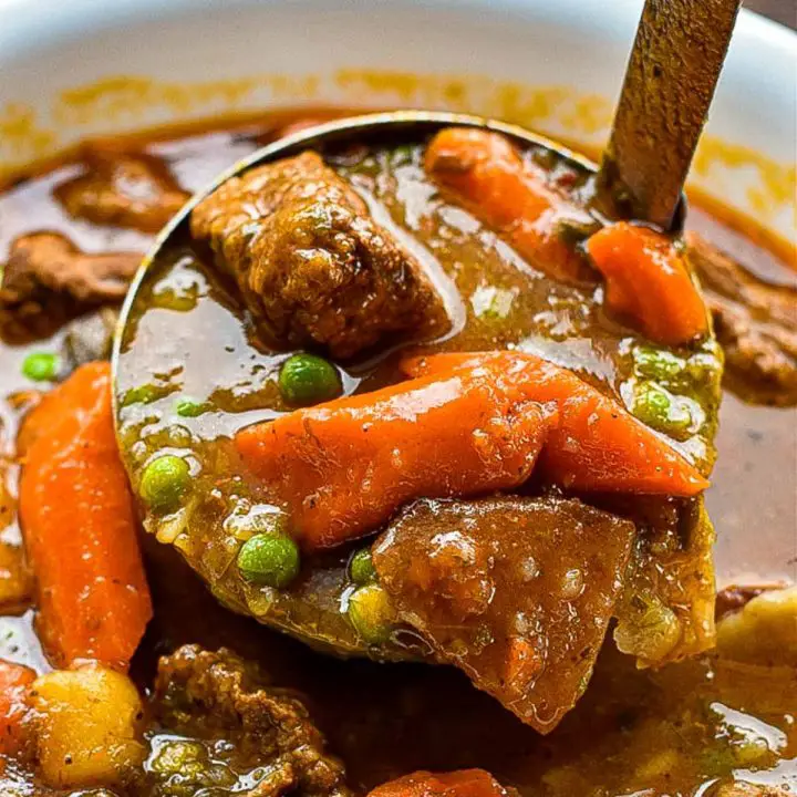 low fodmap beef stew in a ladle over a bowl of stew.