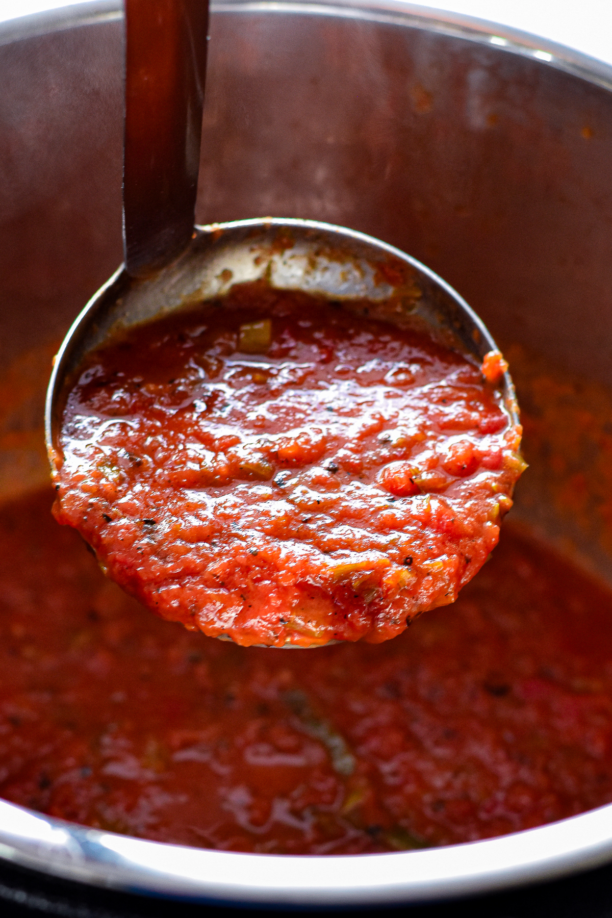 a ladle containing low fodmap pasta sauce over an instant pot full of pasta sauce.