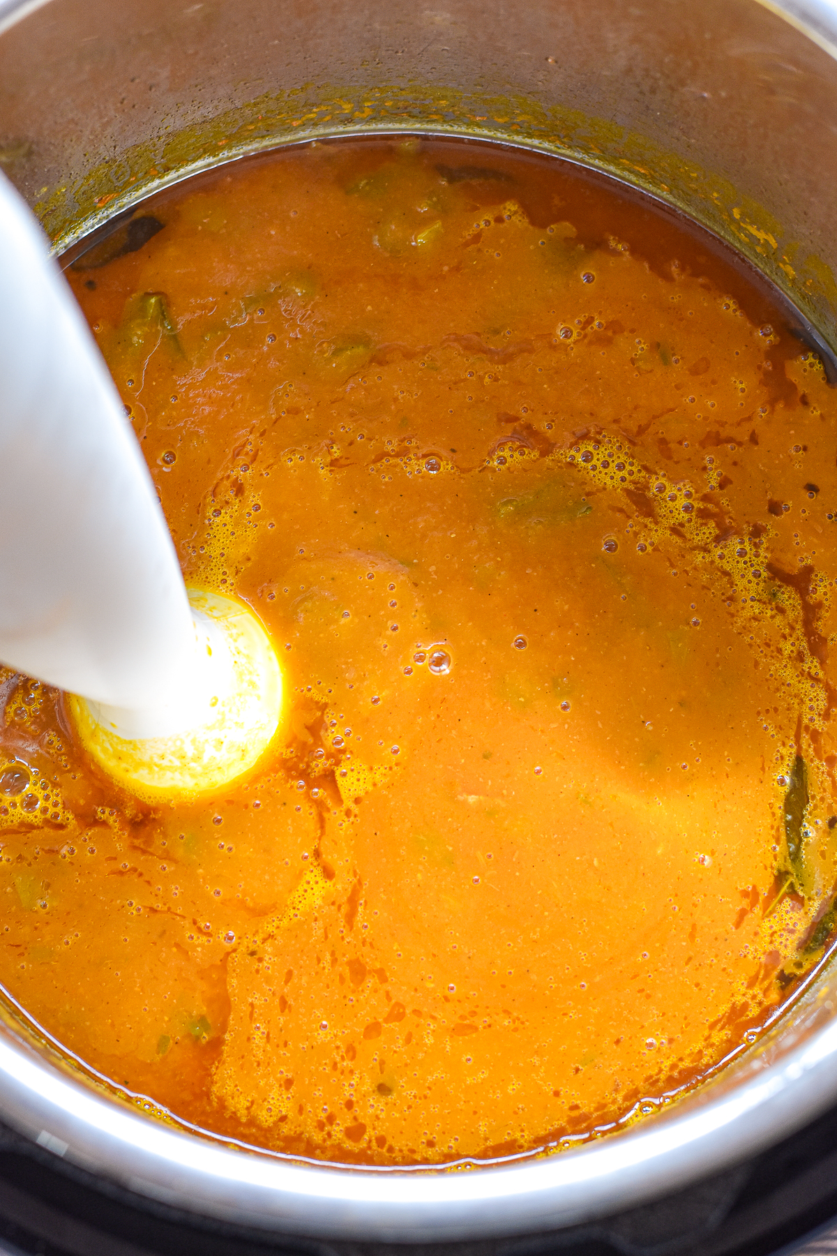 process shot of an immersion blender blending low fodmap pumpkin soup after being pressure cooked.