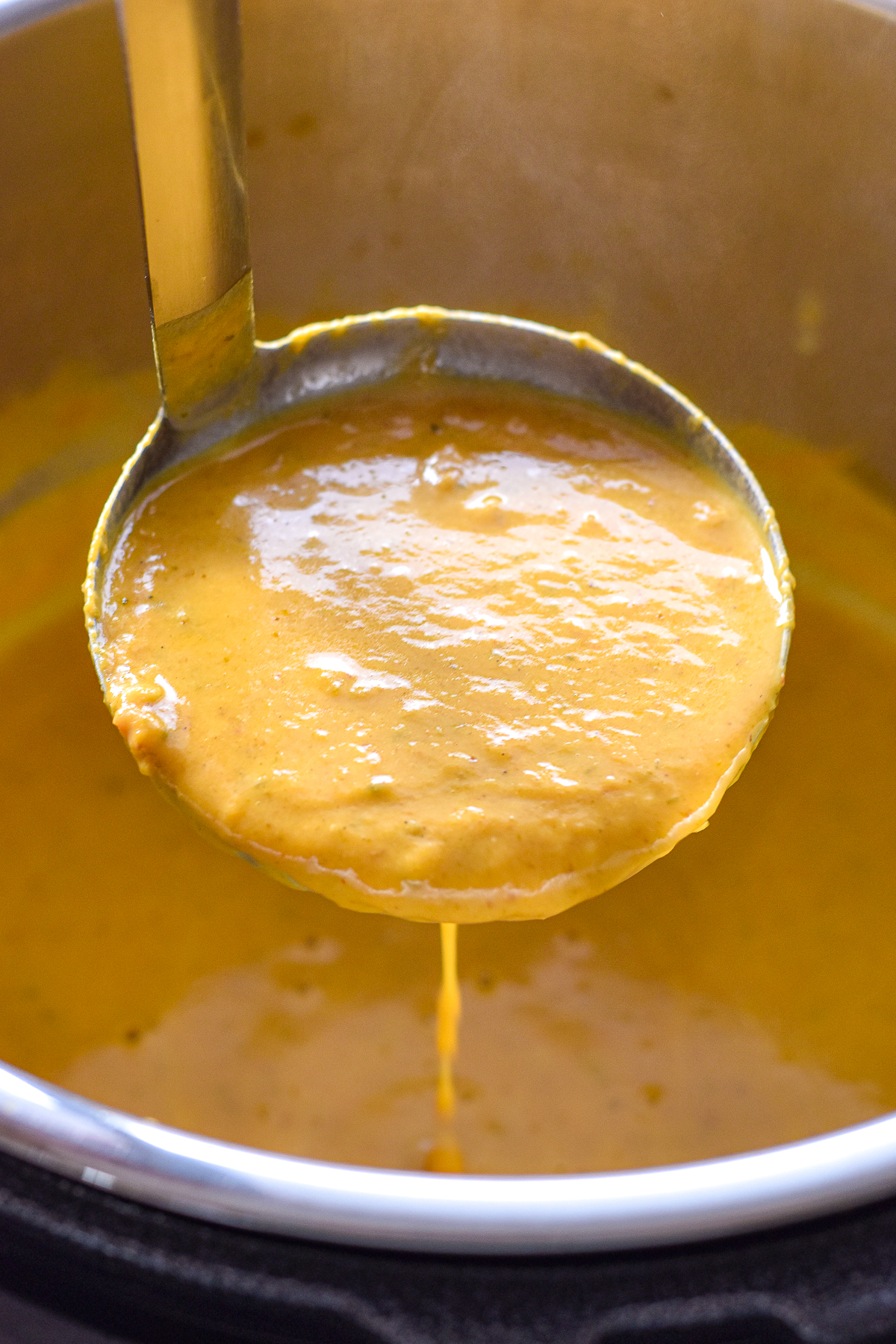 a ladle filled with low fodmap pumpkin soup dripping over an open instant pot.
