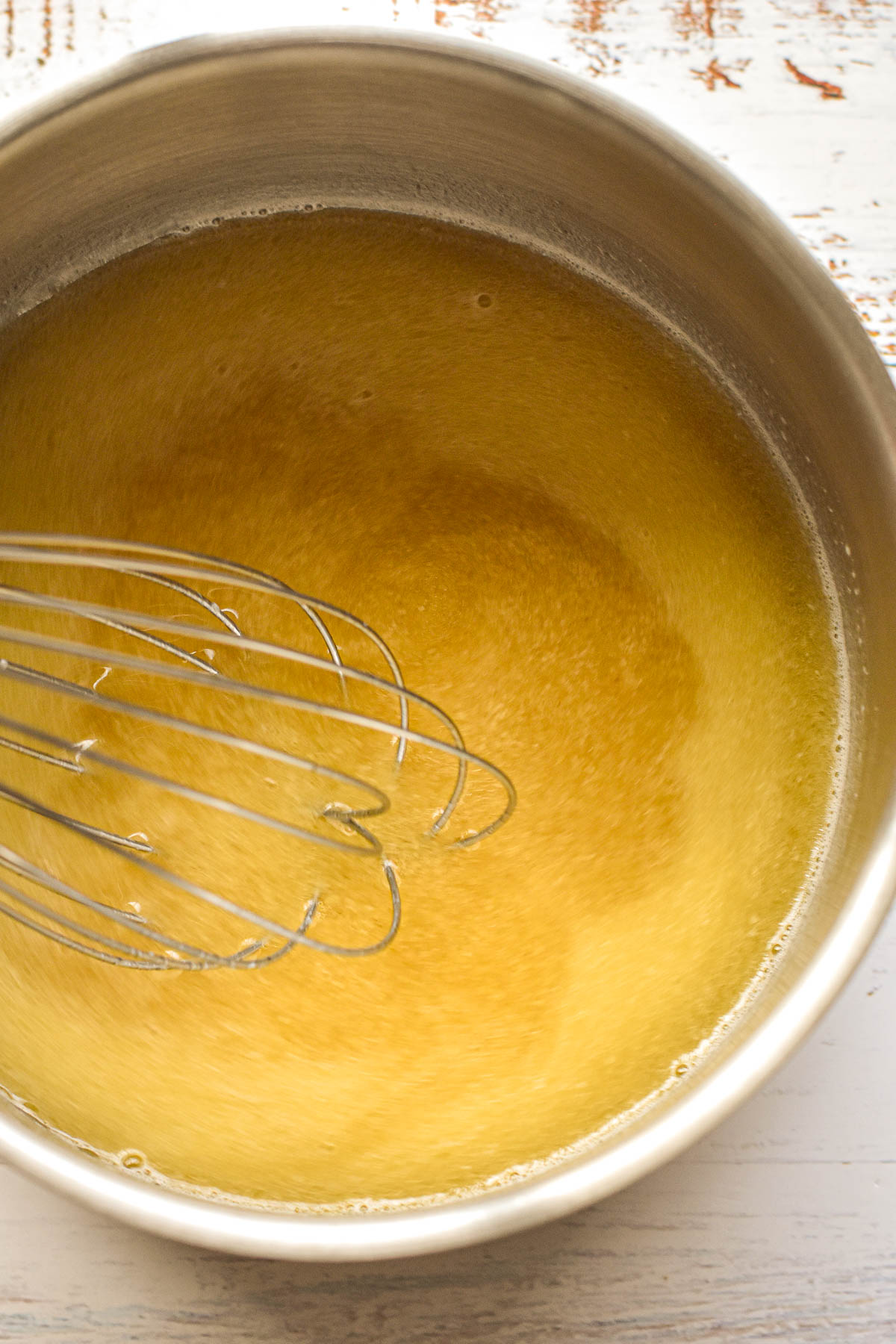 whisking broth into a roux to make gravy in a saucepan.