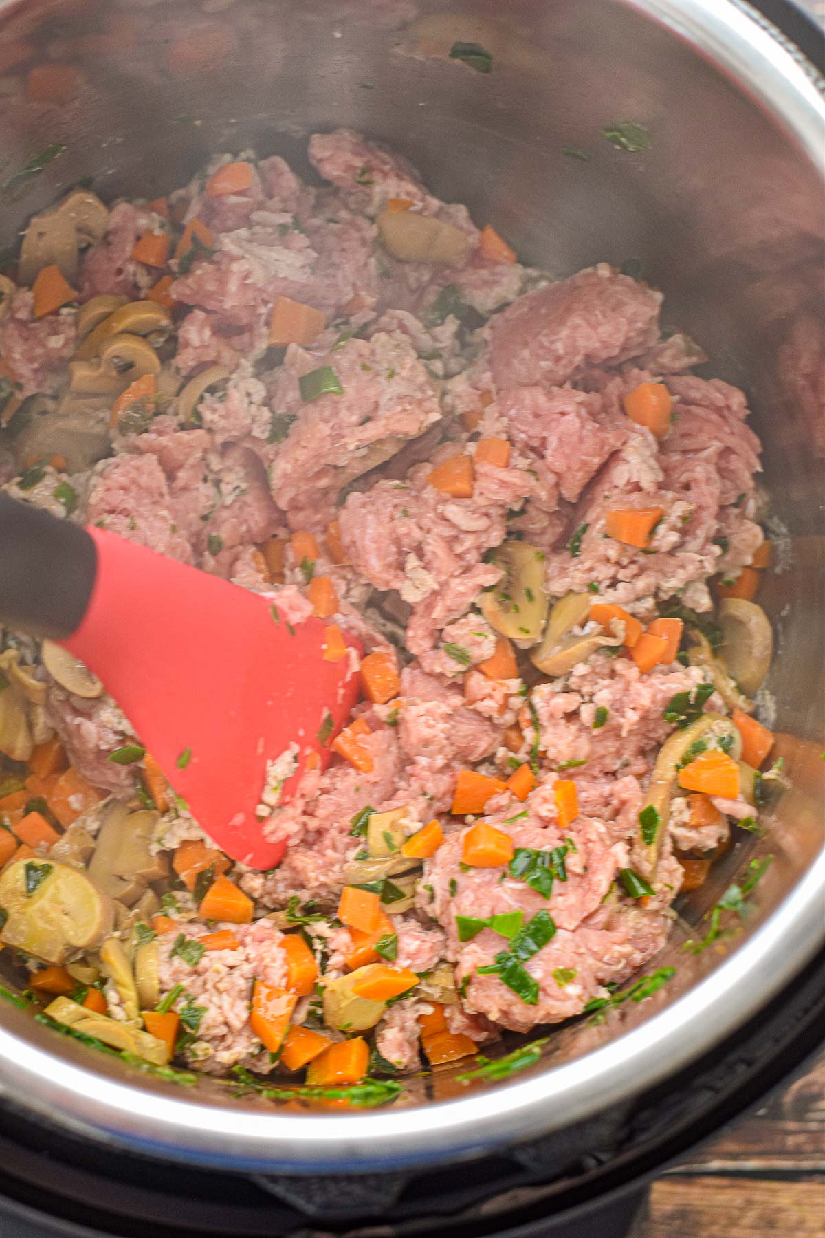 an instant pot spatula breaking up ground turkey and stirring together with sauteed veggies in an instant pot.