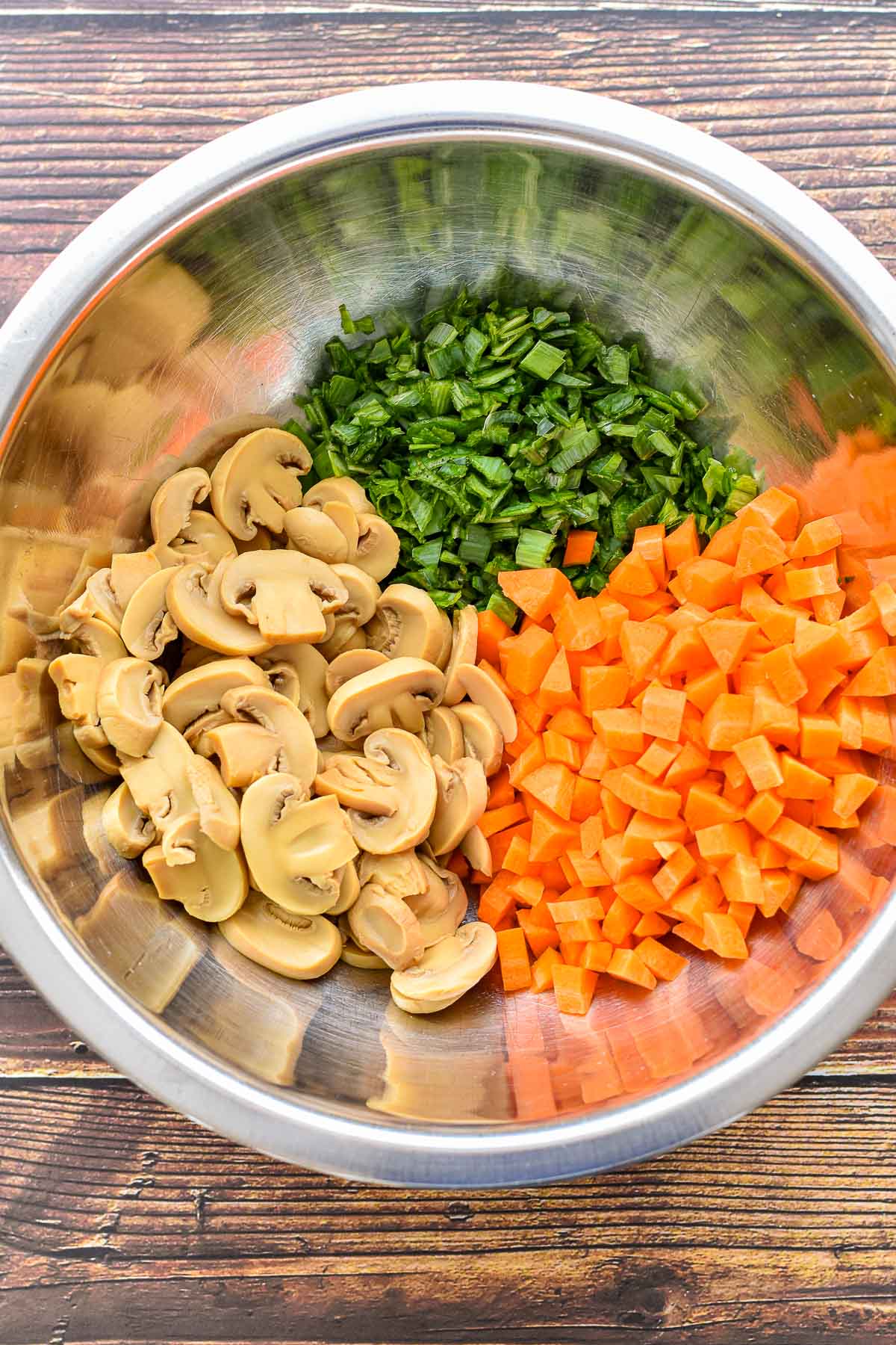 sliced canned mushrooms, finely chopped leek greens and carrots in a large mixing bowl prior to cooking.