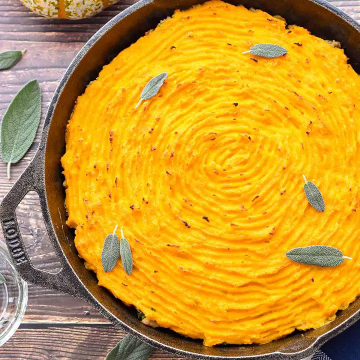 low fodmap low carb shepherd's pie with a squash topping garnished with fresh sage leaves in a cast iron skillet.