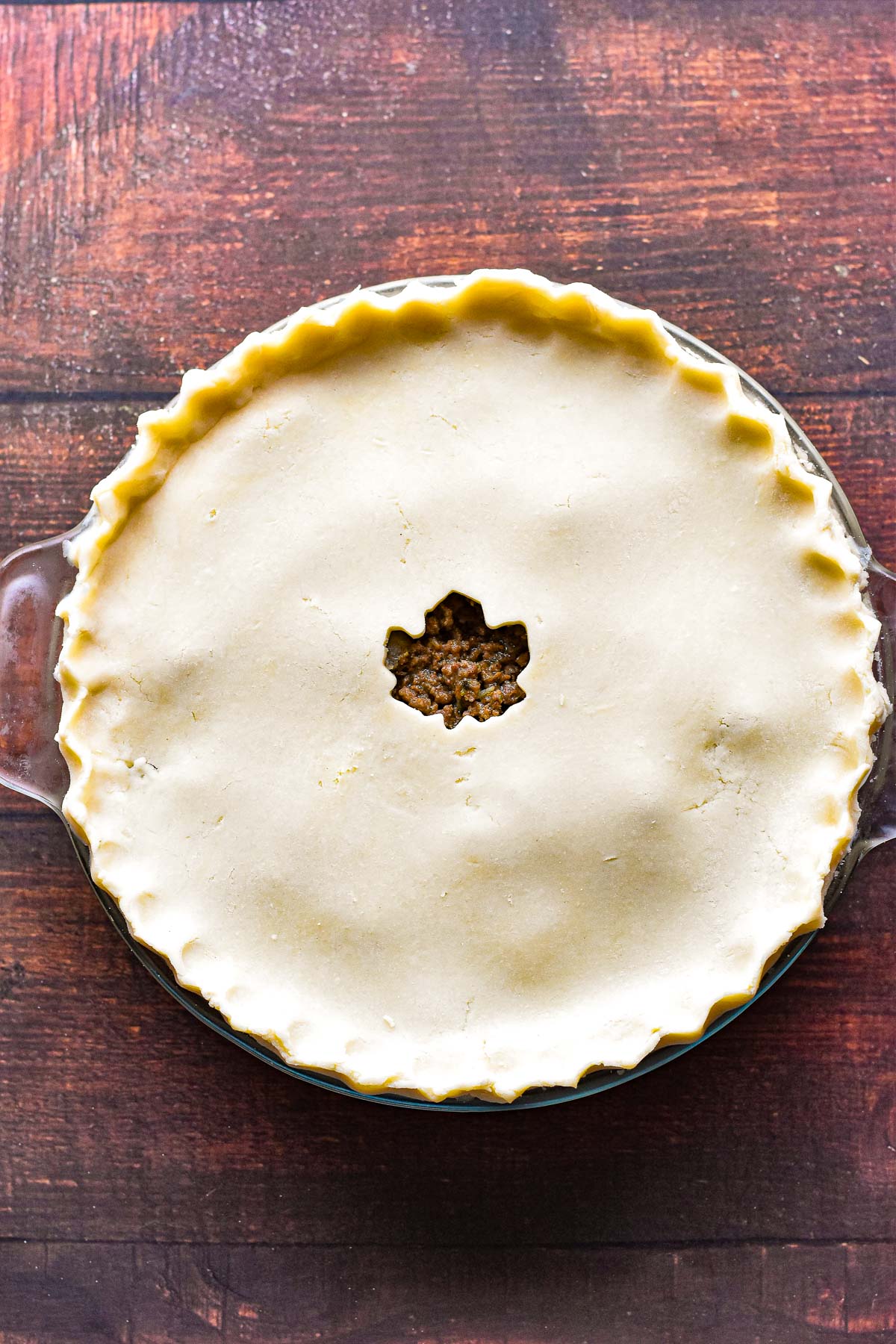 low fodmap tourtiere with the top crust applied and the edges fluted prior to baking.