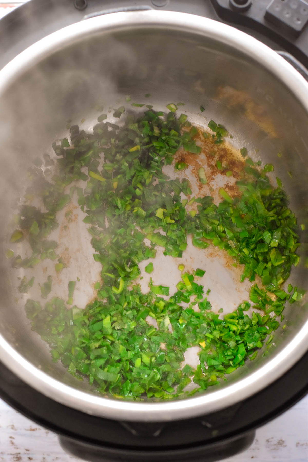 finely chopped leek greens sauteing in an instant pot.