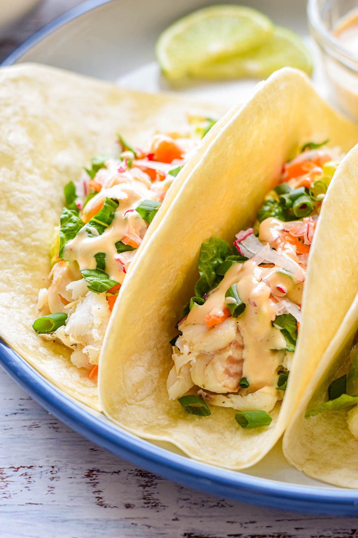 close up shot of low fodmap fish tacos drizzled with spicy mayo.