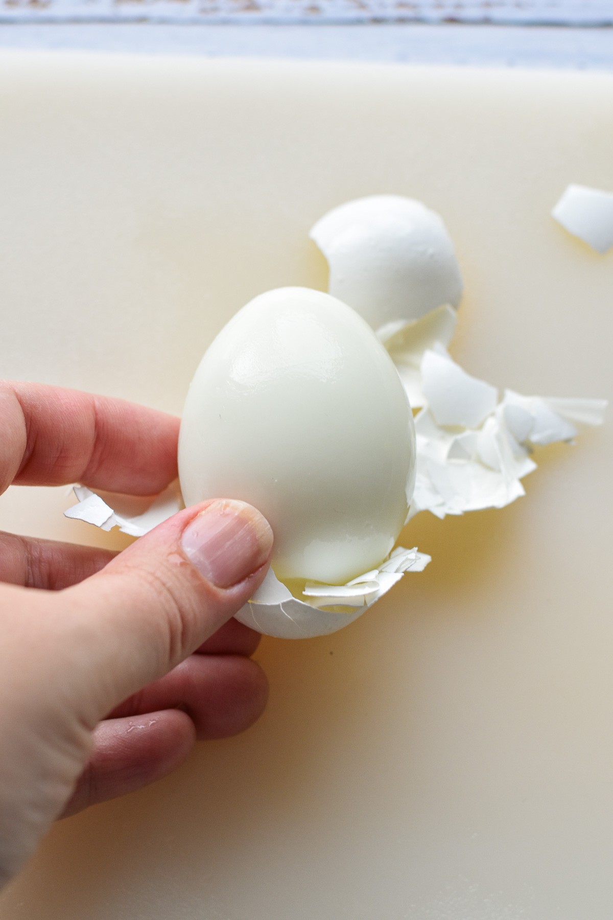 a hand peeling the shell from a hard boiled egg.