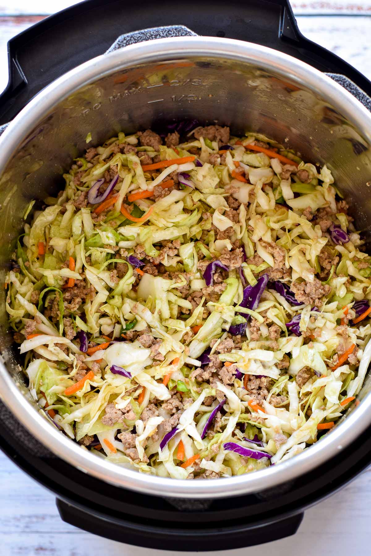overhead shot of the instant pot after coleslaw mix has been stirred in to make egg roll bowls.